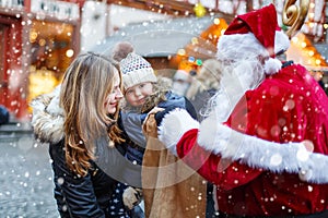 Little toddler girl with mother on Christmas market.