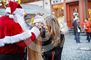 Little toddler girl with mother on Christmas market.