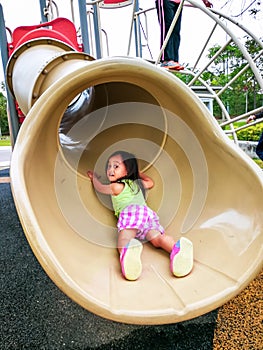 Little toddler girl playing at the slide. Doing upside down position