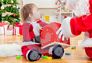 Little toddler girl receiving a gift from Santa Claus