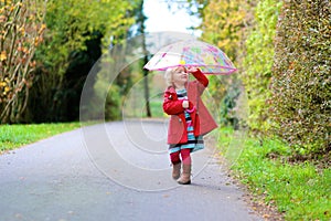 Little toddler girl walking with umbrella