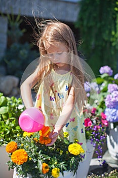 Little toddler girl watering flowers with a