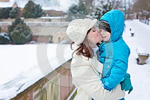 Little toddler kid boy and mother having fun with snow on winter day