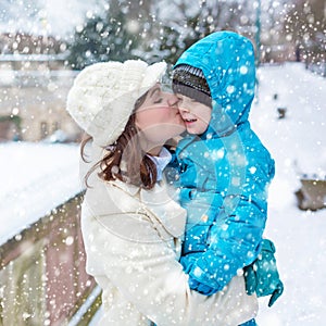 Little toddler kid boy and mother having fun with snow on winter day