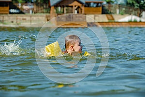 Little toddler kid swimming in lake with inflatable arms aids support