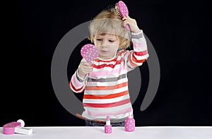 Little toddler playing with make-up toys on