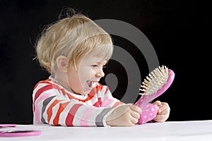 Little toddler playing with make-up toys on