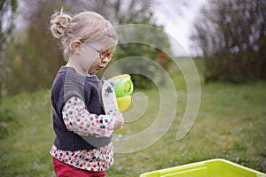 Little toddler playing with sand in the garden