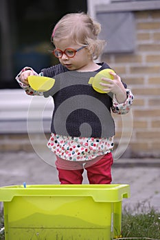 Little toddler playing with sand in the garden