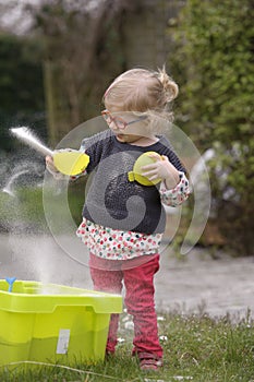 Little toddler playing with sand in the garden