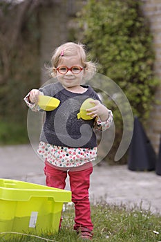 Little toddler playing with sand in the garden