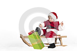 Little toddler in santa claus outfit in the snow