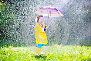 Little toddler with umbrella playing in the rain