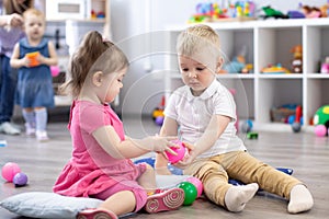 Little toddlers boy and a girl playing together in nursery room. Preschool children in day care centre