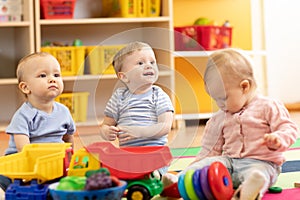 Little toddlers boys and a girl playing together in kindergarten room. Preschool children in day care centre