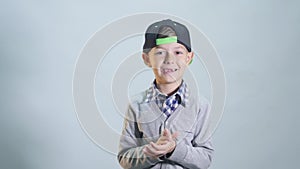 Little toothless boy joyfully clapping hands. Portrait on gray background