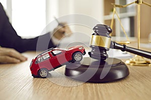 Little toy automobile on lawyer's table illustrating concept of car accident and lawsuit