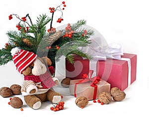 Little toy puppy, christmas tree branches, nuts and some gifts on a white background