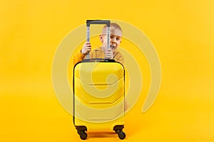 Little traveler tourist kid boy 3-4 years old isolated on yellow orange wall background studio. Passenger traveling