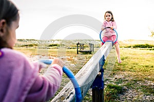 Little twin girls children are riding seesaw swing in park.