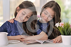 Little twin girls reading a magazine