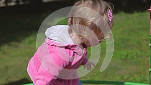 Little two year old blond girl in jeans plays in a children's park, children slide