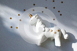 Little unicorn on a shiny white background with stars. The concept of magic, childhood dreams, a modern trend for universal