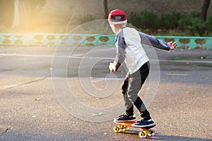 Little urban boy with a penny skateboard. Young kid riding in th