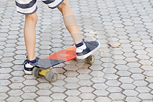 Little urban boy with a penny skateboard. Young kid riding in th