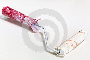Little used dried paint roller on white surface photo