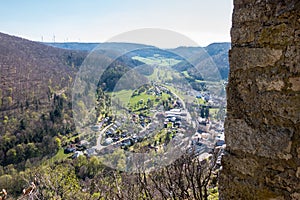 Little village in the middle of the german countryside with hills, forests, fields and meadows and the walls of a castle