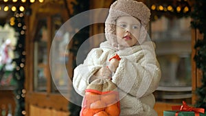 Little warmly dressed girl is holding a bag of tangerines. At the Christmas market.