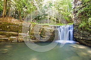 Little waterfall in mountain forest with silky foaming water