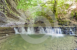 Little waterfall in mountain forest with silky foaming water