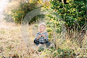 Little whimpering girl sitting on the lawn under sunlight