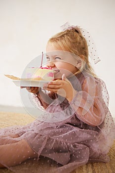 Little white Birthday girl with cake in a pink dress laughs. Preschooler.