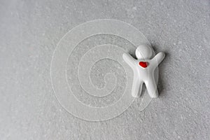 Little white ceramic man with heart on gray paper background