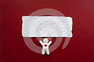 Little white ceramic man with heart and Little white ceramic man with heart and white card on red background