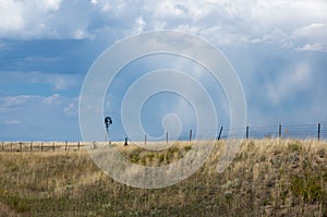 Little Windmill in a golden wheat fied against a blue sky with clouds