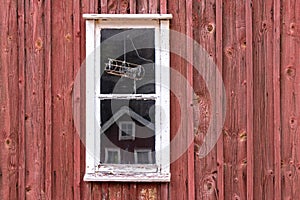 A little window in front of a typival scandinavian building with falu red photo