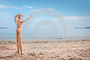 Little wooden manikin looking out towards Lake Victoria from the golden sandy shore line, Entebbe, Uganda