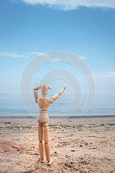 Little wooden manikin looking out towards Lake Victoria from the golden sandy shore line, Entebbe, Uganda