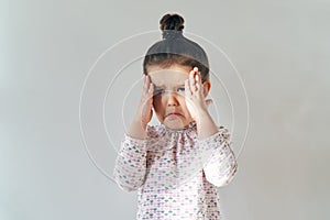 little young girl with her hair gathered on top posing for a portrait in natural light with a disturbed crying expression, by