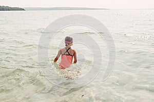 Little young girl swimming in lake river with underwater goggles. Child diving in water on a beach. Authentic real lifestyle happy