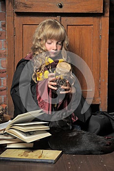 Little young witch with black cat and books