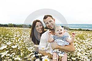 Littlegirl and his father and mother enjoying outdoors in field of daisy flowers