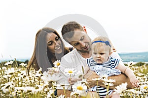 Littlegirl and his father and mother enjoying outdoors in field of daisy flowers