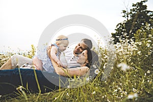 Littlegirl and his father and mother enjoying outdoors in field of daisy flowers