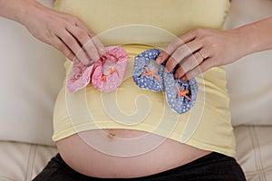 The littlest feet make the biggest footprints in our hearts. a young pregnant woman holding a pair of pink and blue baby photo