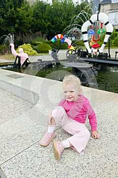 littlle girl sitting by modern fountain by Niki de Saint Phalle photo